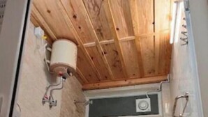 A compact bathroom with a wooden ceiling, a shower stall, and a toilet. - Veda Cottage (Barkot)