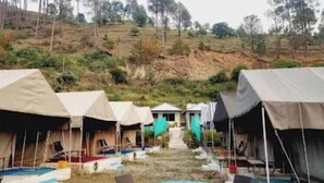 A campsite with tents, a round table, and chairs. - Veda Cottage (Barkot)