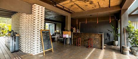A modern bar area with a brick wall, a chalkboard menu, and a seating area with stools.