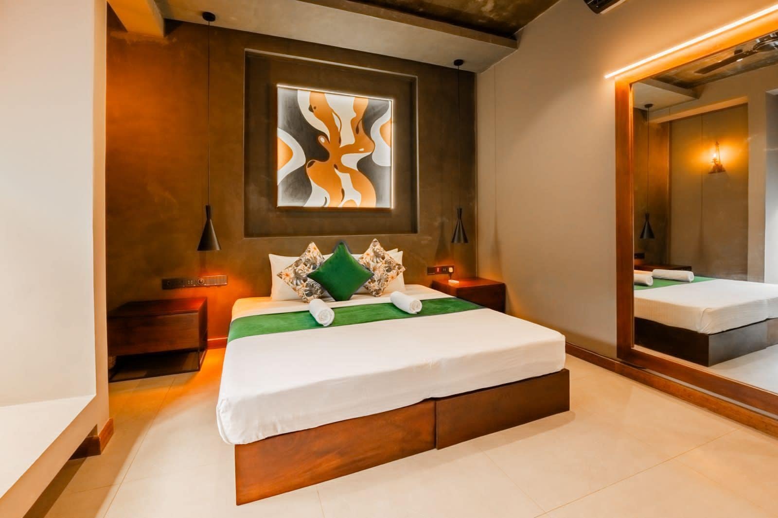 A modern bedroom with a large bed, a green throw, and a large mirror.