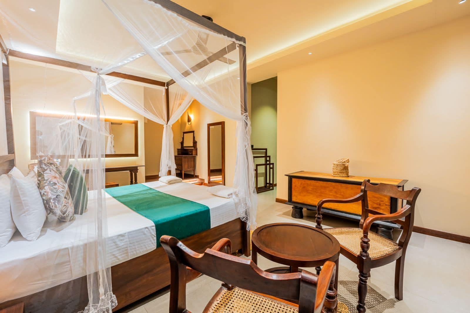 Quarto de hotel com uma cama, uma escrivaninha de madeira, uma cadeira e uma pequena mesa.