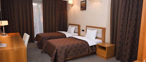 A hotel room with two beds, a desk, and a nightstand.