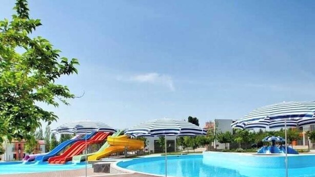 Un espace piscine avec des toboggans et des parasols.