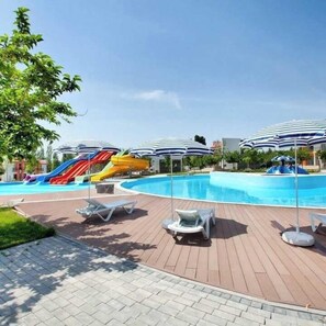 Un espace piscine avec des toboggans et des parasols.