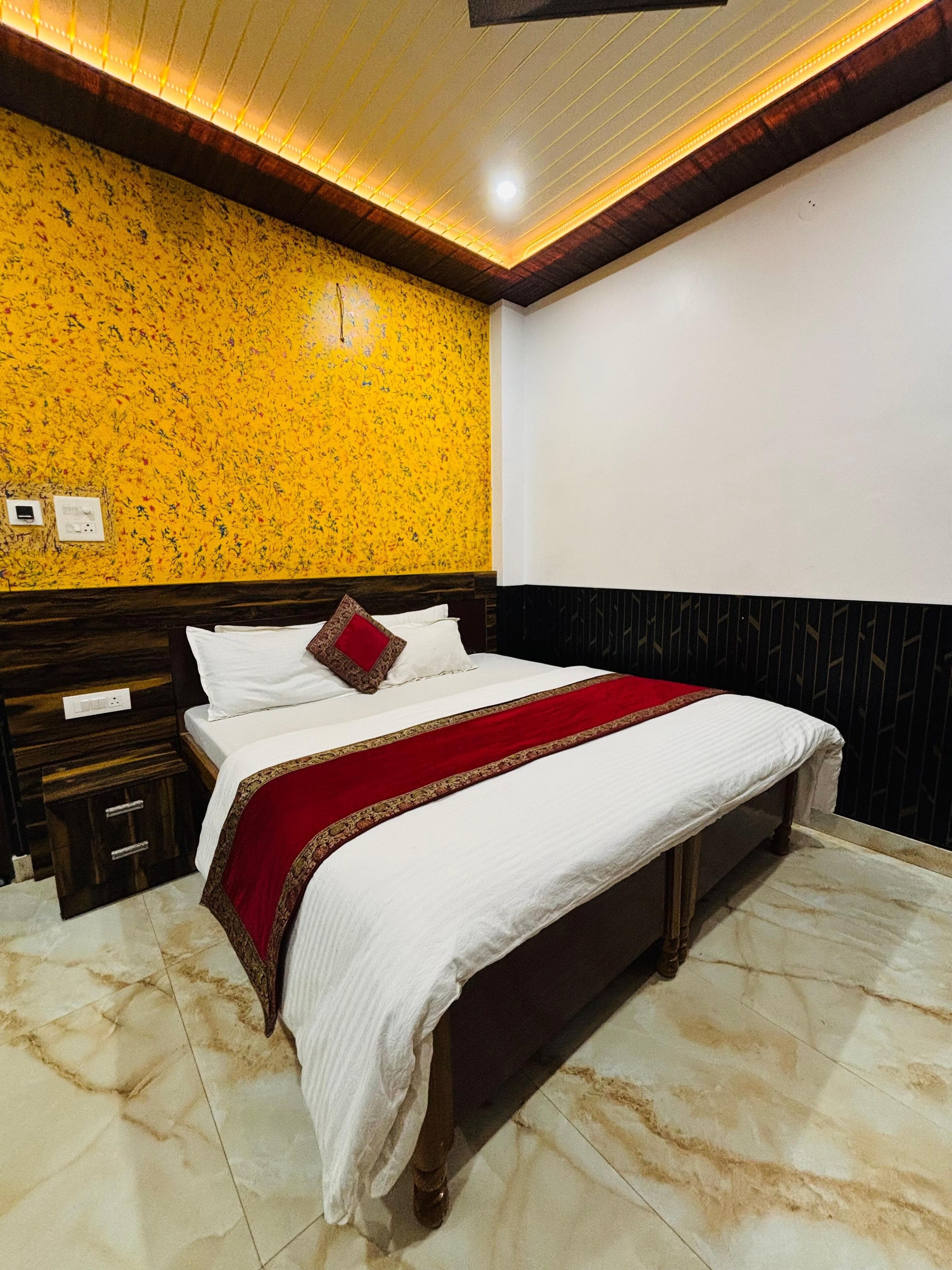 A bedroom with a bed, wooden headboard, marble floor, and a yellow patterned wall.
