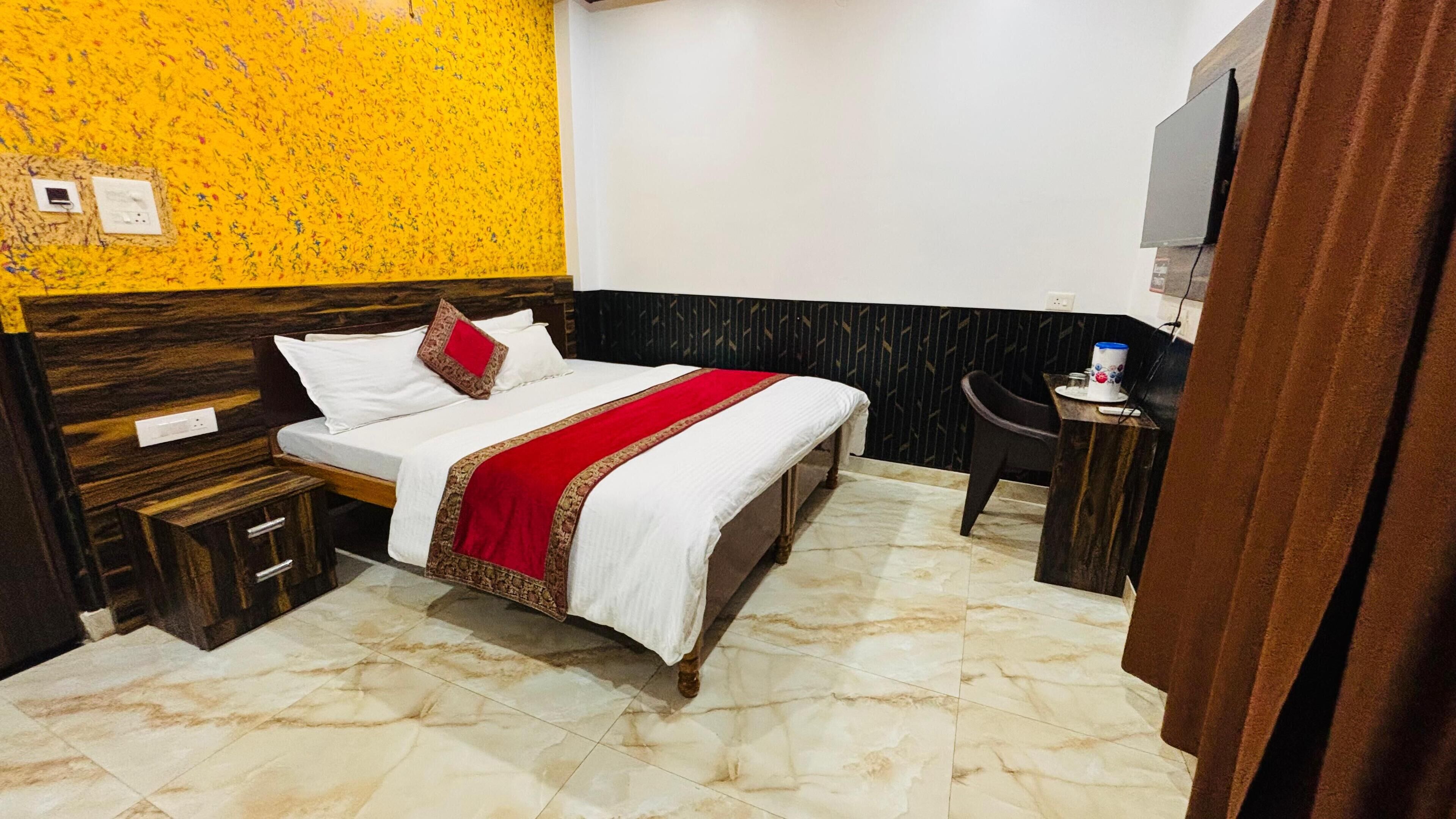 A hotel room with a bed, a small table, a chair, and a TV.