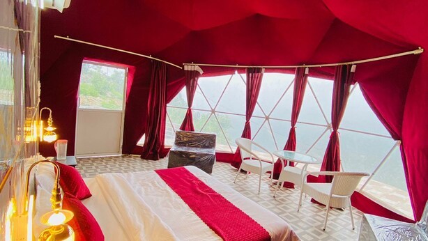 A tent-style room with a bed, a table, chairs, and a view through large windows. - HR 26 Hotels & Resorts (Rishikesh)
