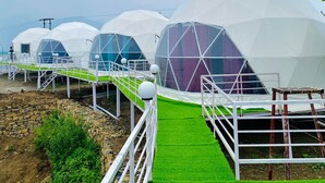 A row of dome-shaped structures with a green pathway leading to them. - HR 26 Hotels & Resorts (Rishikesh)