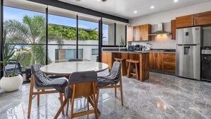 Una cocina moderna con una isla grande, electrodomésticos de acero inoxidable y vistas a la vegetación.
