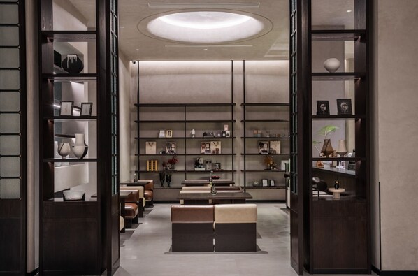 Un intérieur moderne avec un espace salon central, des étagères remplies de divers objets et un luminaire au plafond.