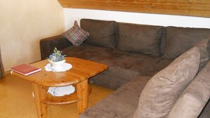 Un salon avec un canapé marron, une table basse en bois ornée d’une plante et d’un livre, et un coussin à motifs.