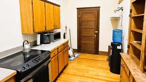 Una cocina compacta con muebles de madera, una estufa negra y un dispensador de agua.