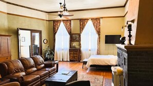 Una sala de estar acogedora con un sofá de cuero, una mesa de centro, una chimenea y una cama con colcha blanca.