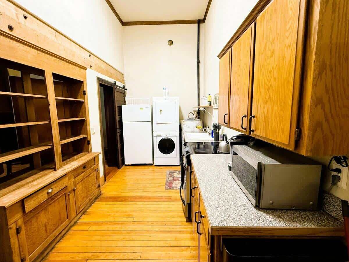 Una cocina compacta con armarios de madera, lavadora integrada y microondas.