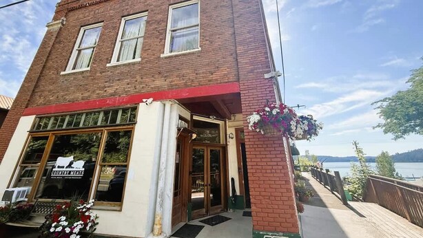 Un edificio de ladrillo de dos pisos con un toldo rojo y un escaparate que dice 'COUNTRY MEATS'.
