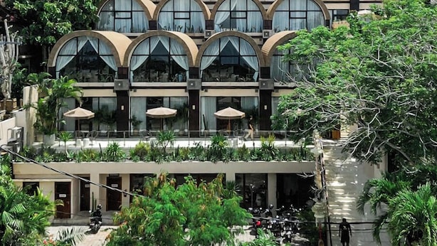 A hotel with multiple levels, large arched windows, and a central courtyard with greenery. - Sunny Samudra  (Pecatu)