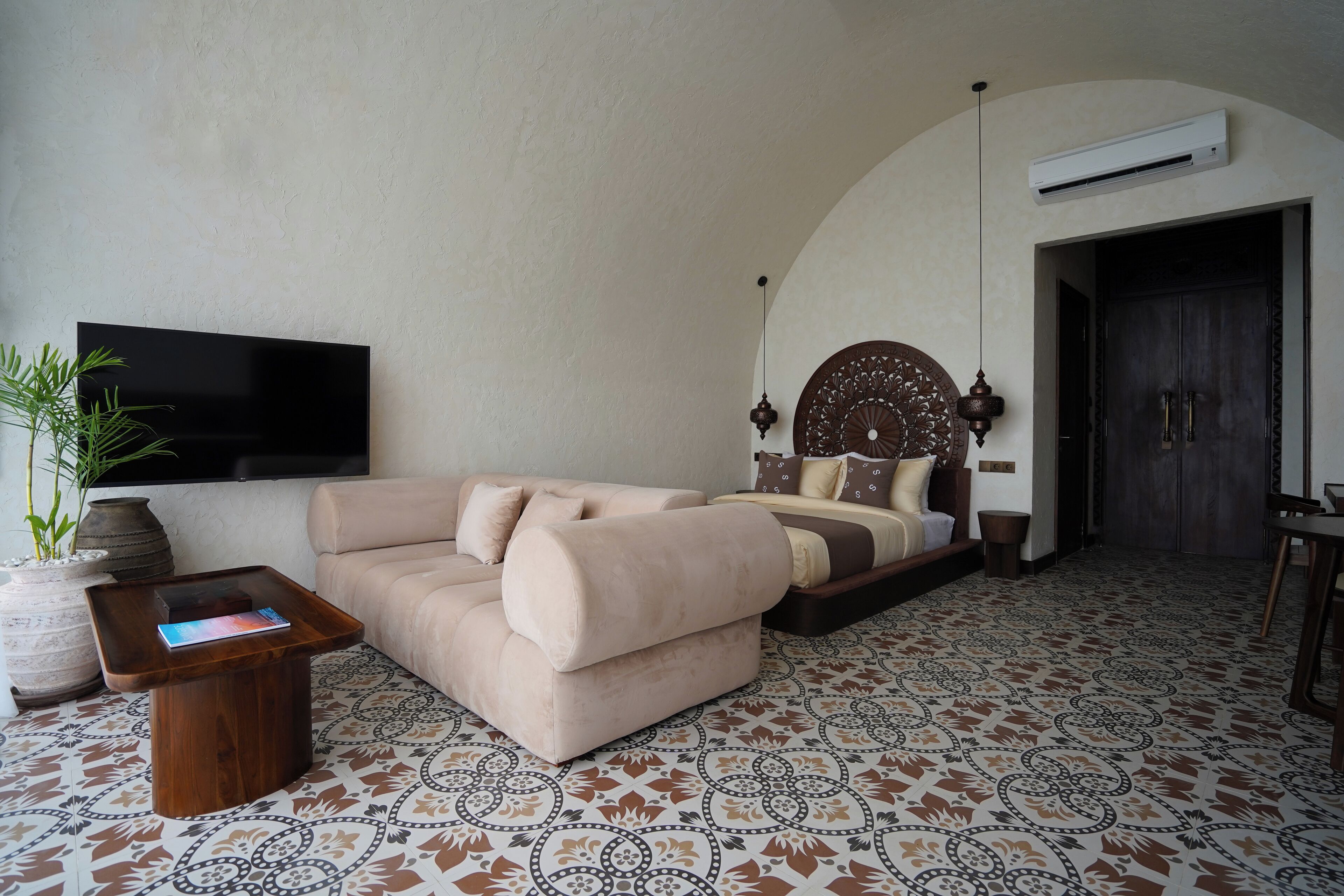 A living room with a sofa, a coffee table, a TV, and a patterned floor.