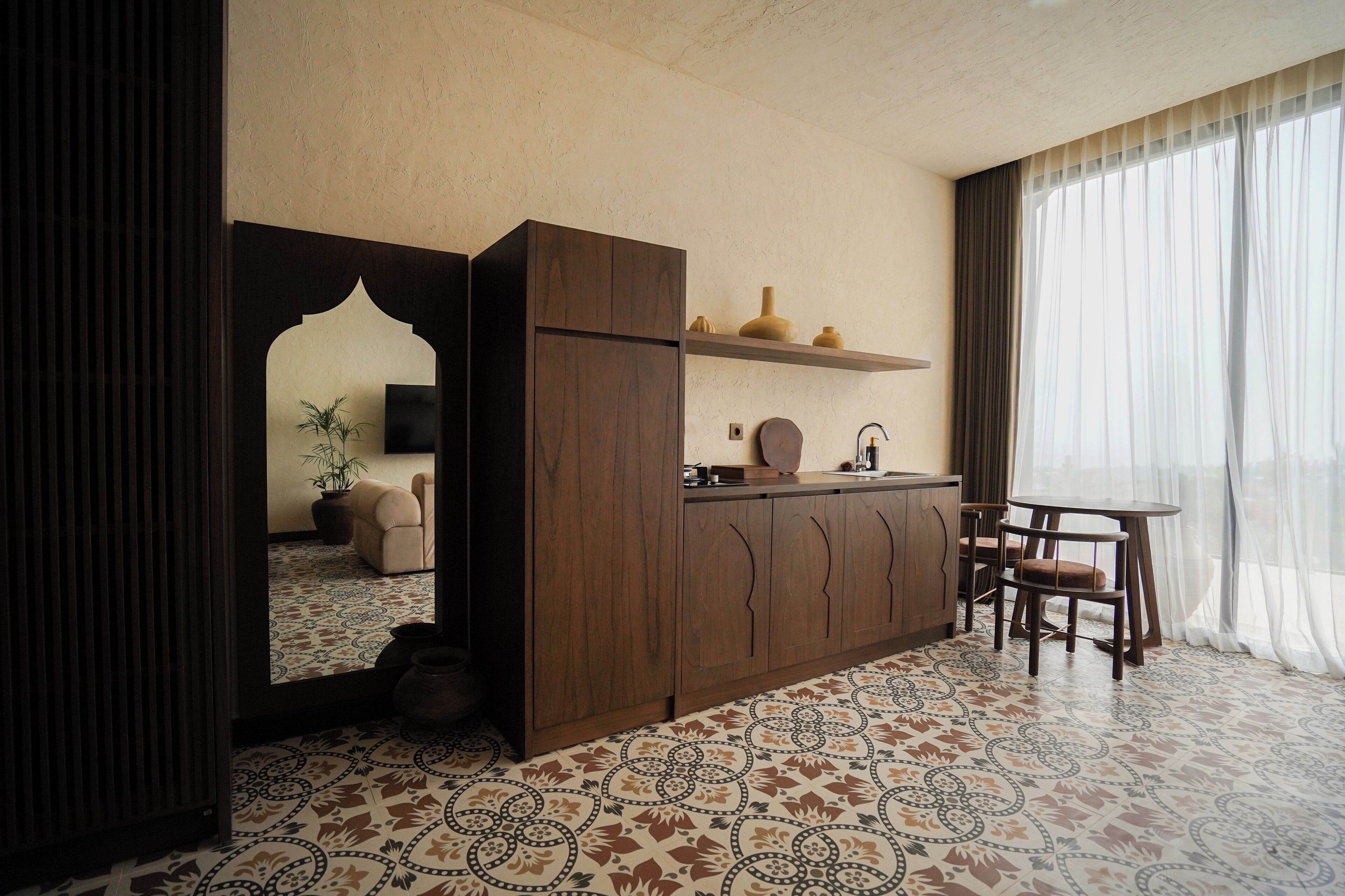 Een kleine kamer met een kitchenette, een eethoek en een grote spiegel.