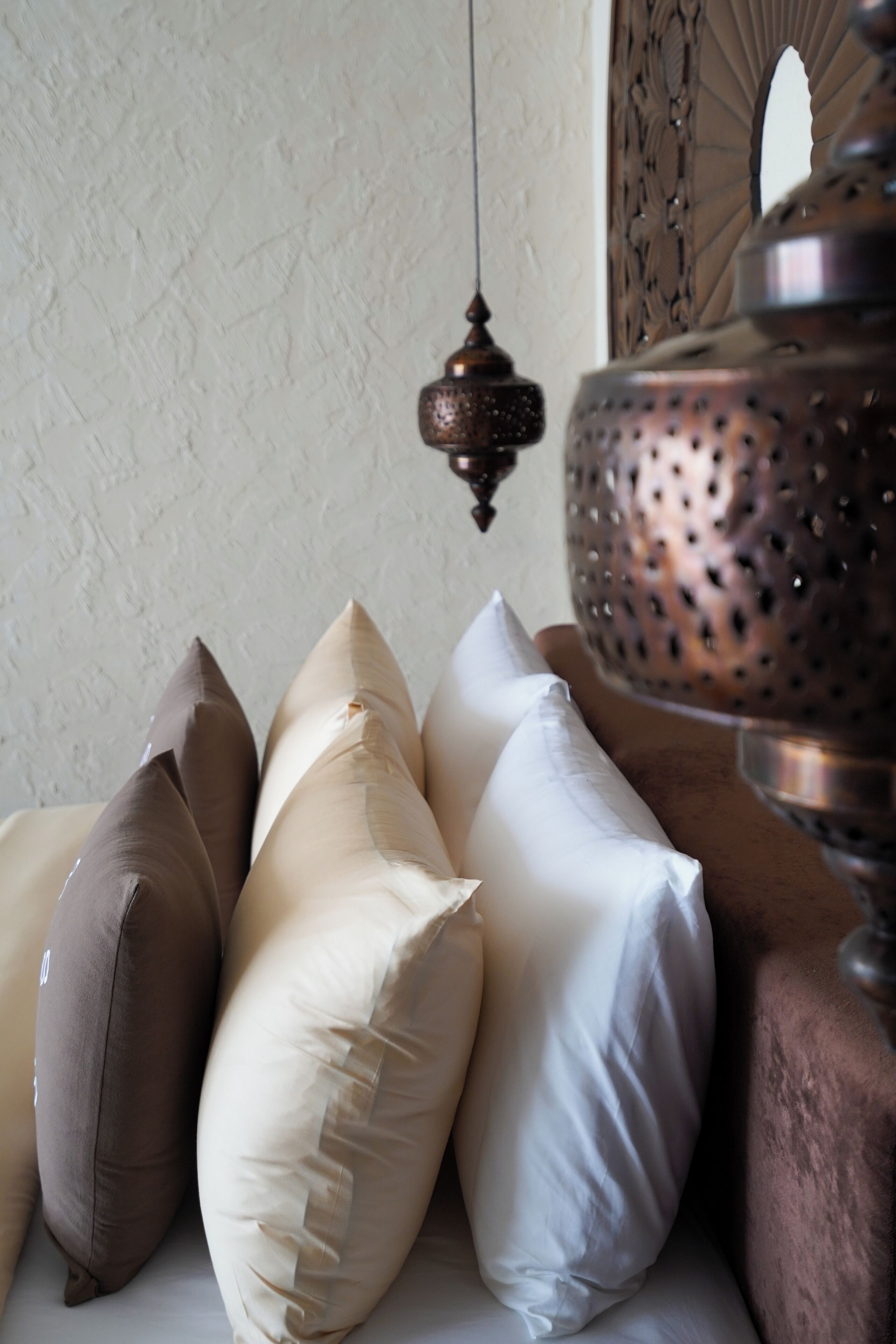 A collection of pillows in various shapes and sizes, a hanging light fixture, and a decorative metal object.