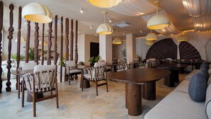 A spacious dining area with high wooden columns, multiple dining tables, and modern pendant lighting. - Sunny Samudra  (Pecatu)