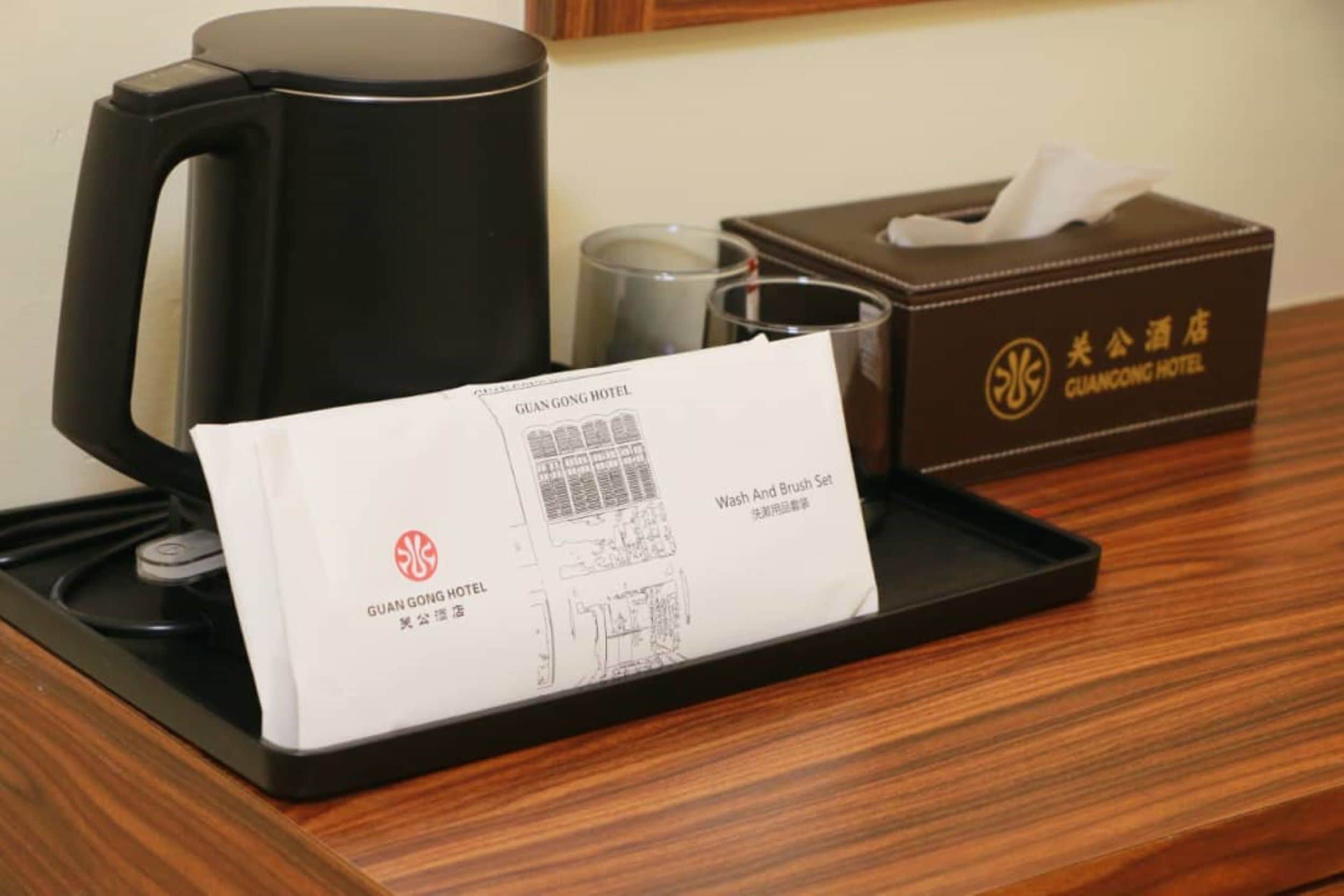 A hotel room with a coffee maker, a tissue box, and a tray with a hotel brochure.