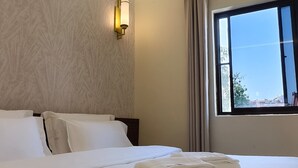 A hotel room with a large bed, a nightstand, a wall-mounted light, a window with curtains, and a view of the outside. - Guan Gong Hotel Jin Shang Development Jonker Street (Malacca City)