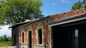 Un bâtiment avec une façade en briques, une allée gravillonnée et une terrasse en bois.