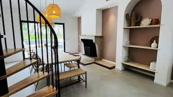 Un intérieur moderne avec un escalier en bois, un coin repas, une cheminée et une bibliothèque.