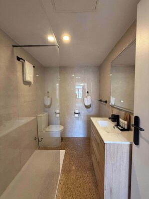 A modern bathroom with a bathtub, toilet, and sink. - Nogalera- Apartamento reformado (Torremolinos)