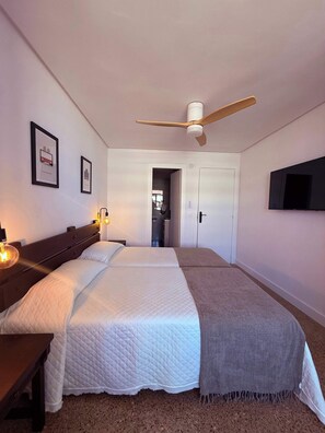 A bedroom with a bed, bedside tables, a ceiling fan, a TV, and framed pictures on the wall. - Nogalera- Apartamento reformado (Torremolinos)