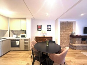 A modern kitchen with a dining area, a stone fireplace, and artwork on the wall.