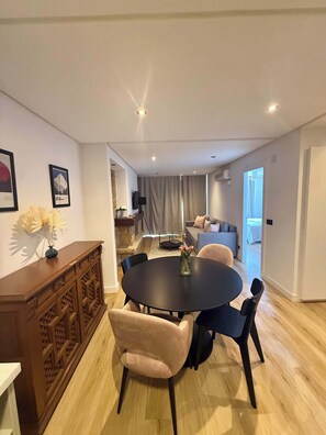 A modern living room with a round dining table, two sofas, a TV, and a staircase leading to another level.