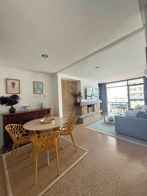 A living room with a dining area, a stone fireplace, and a large window with a view. - Nogalera:: Apartment with sea views and pool. (Torremolinos)
