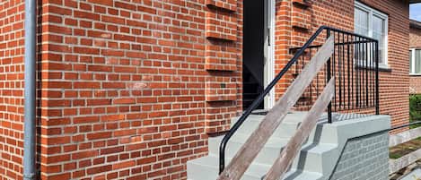 A red brick building with a number 10 sign, a door, and a staircase with a metal railing.