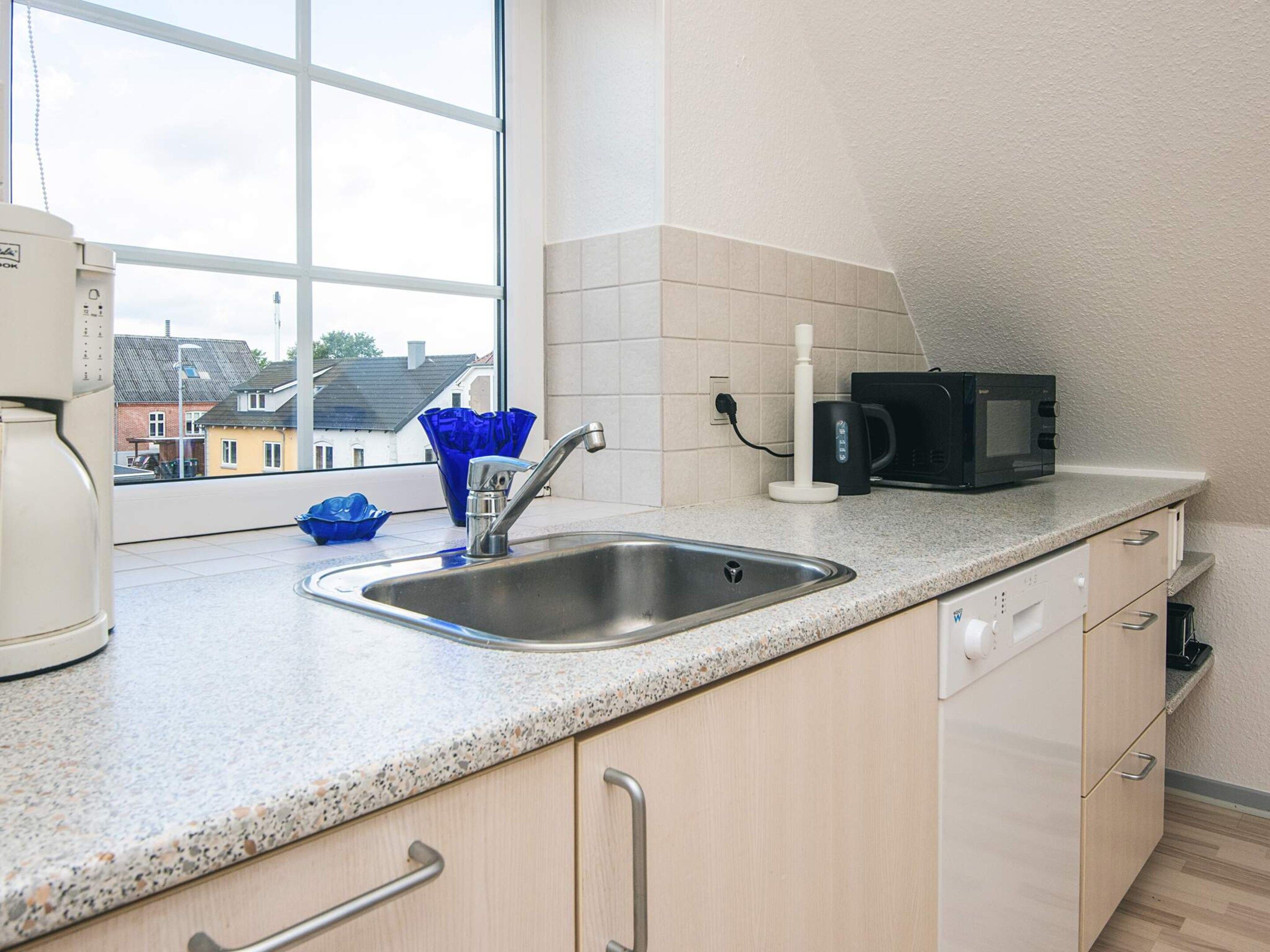 A kitchen with a stainless steel sink, a microwave, and a coffee maker on the countertop.