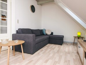 A modern living room with a grey sectional sofa, a small wooden table, and a lamp on a side table.