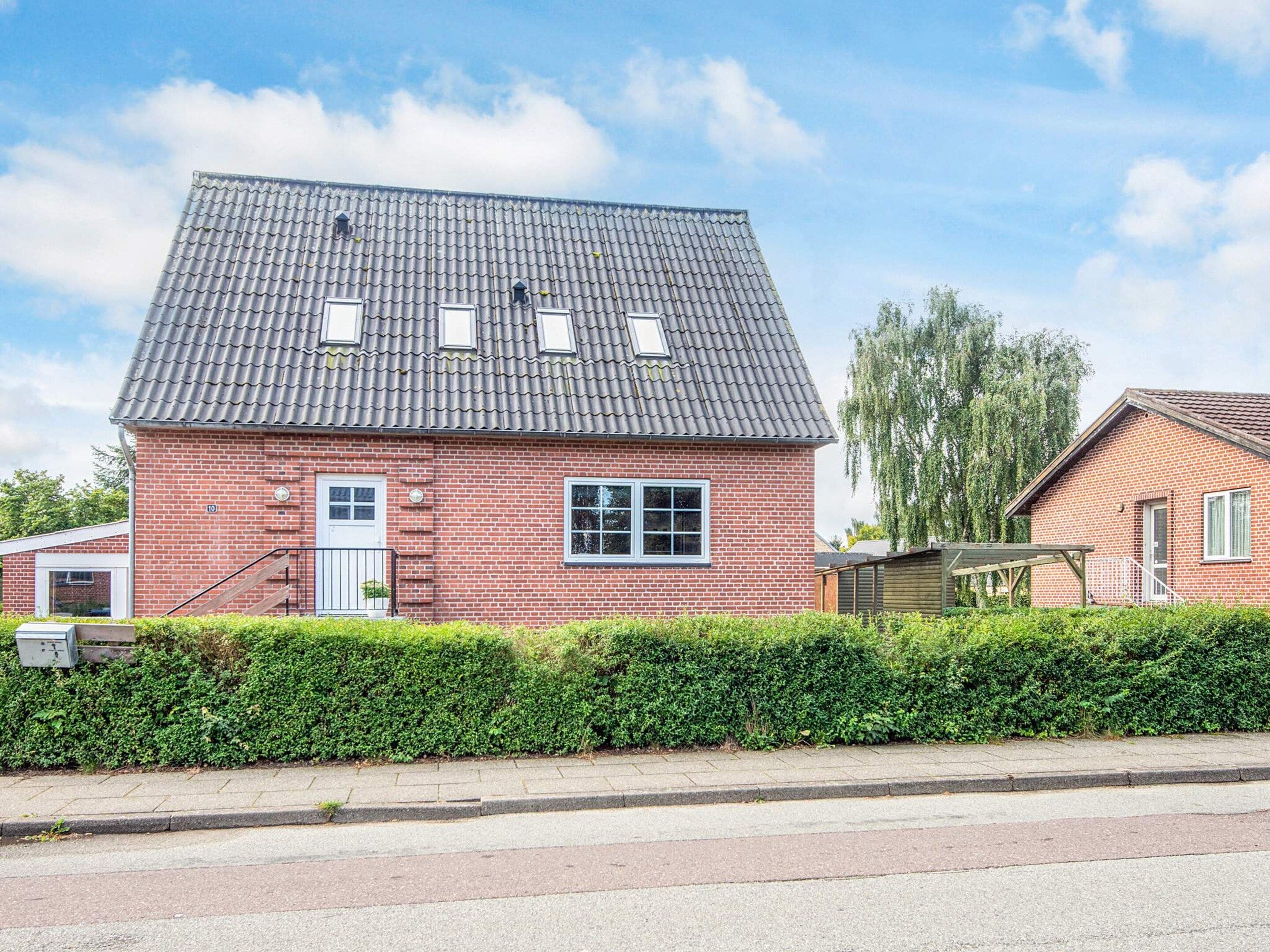 A red brick house with a grey tiled roof, a front door, and a small window.