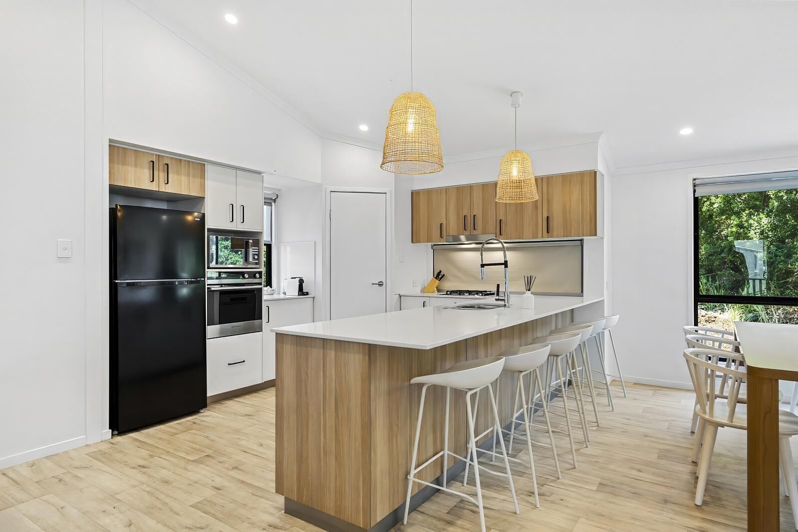 A modern kitchen with a central island, bar stools, and pendant lighting.