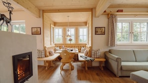 A cozy room with a fireplace, wooden furniture, and large windows. - Chalet Near Lake Grundlsee (Grundlsee)