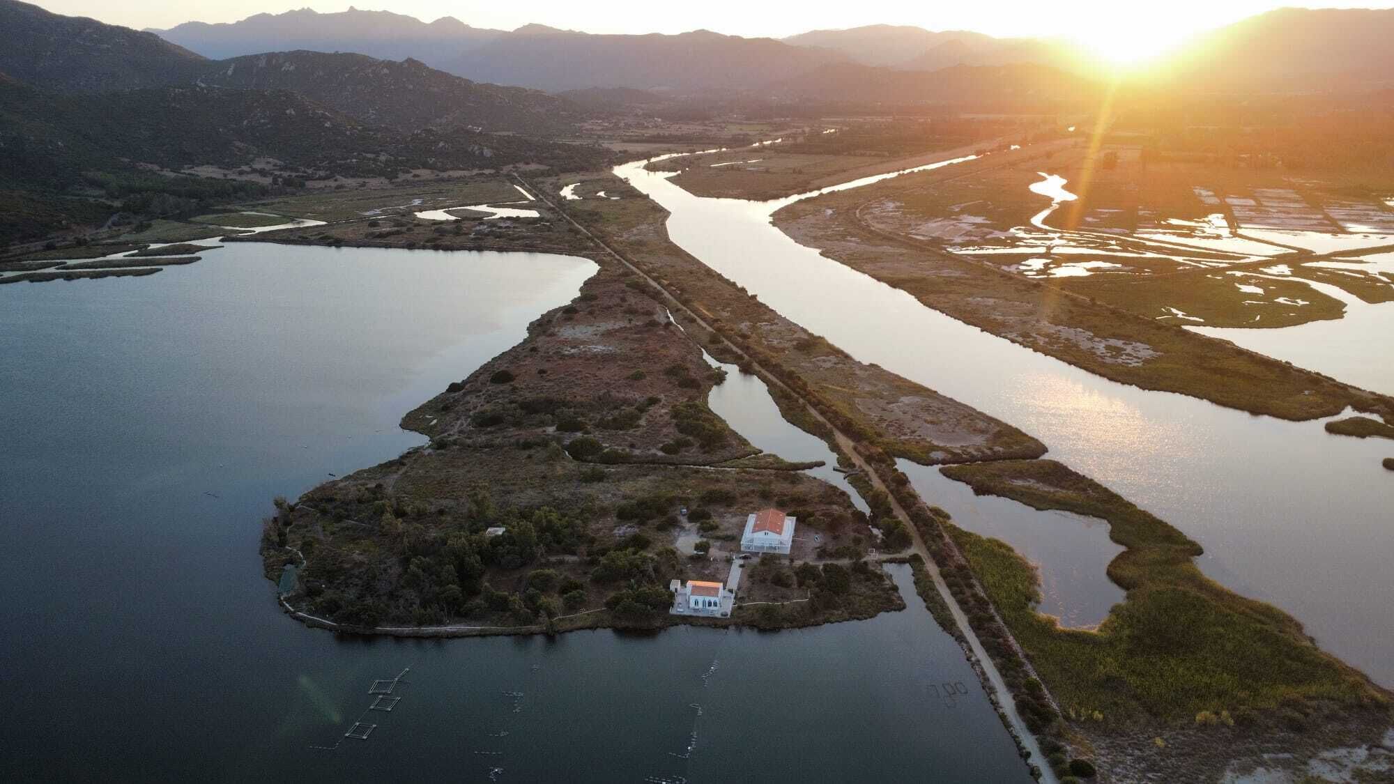 An aerial view of a riverside property with a small house and dock.