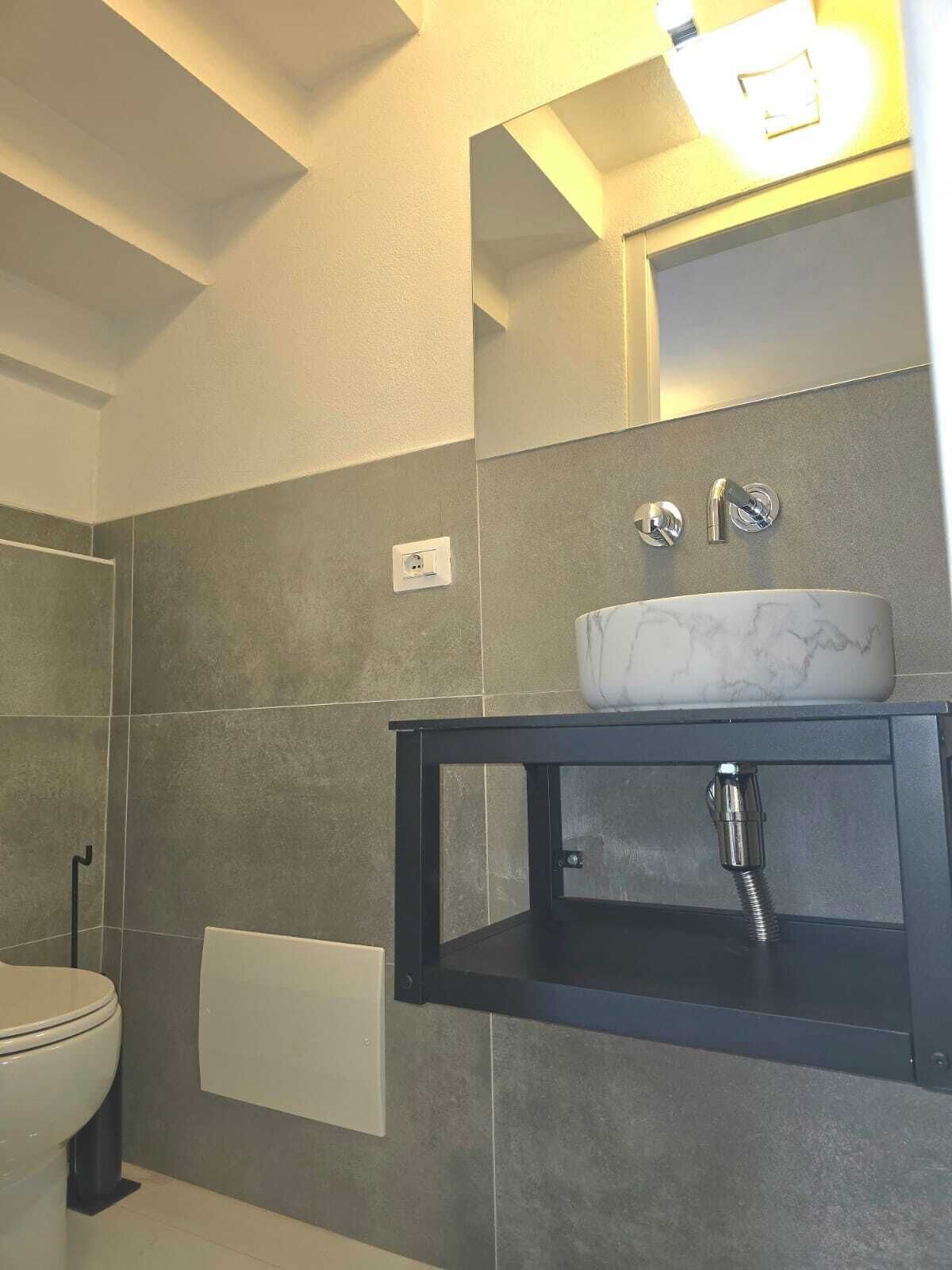 A modern bathroom with a marble sink, a towel rack, and a mirror above the sink.