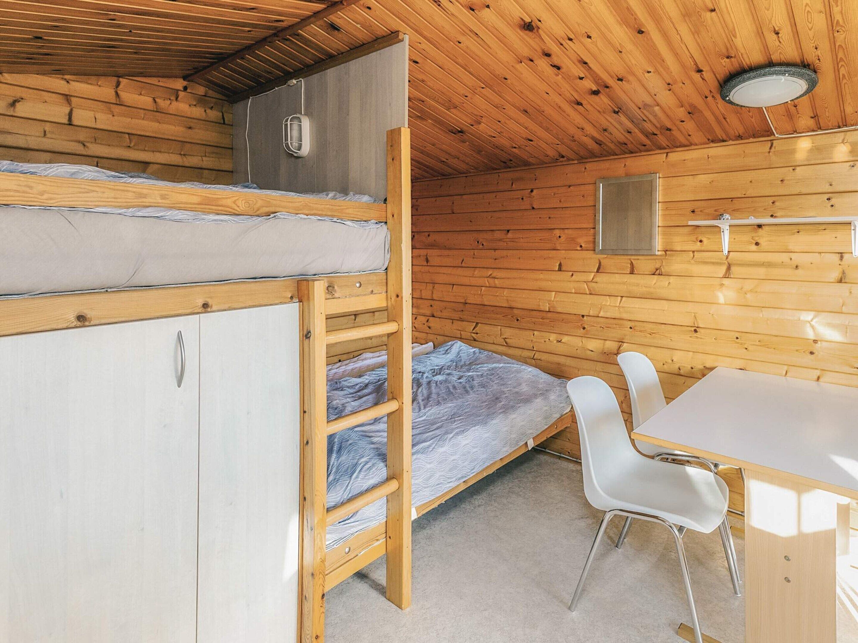 A cabin with a bunk bed, a desk, and a chair.