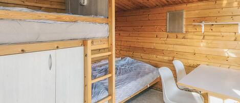 A cabin with a bunk bed, a desk, and a chair.