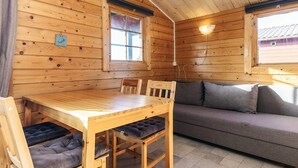 A wooden cabin interior with a wooden dining table, four chairs, a sofa, and two windows. - 3 Person Holiday Park Home in Gorlev (Gørlev)