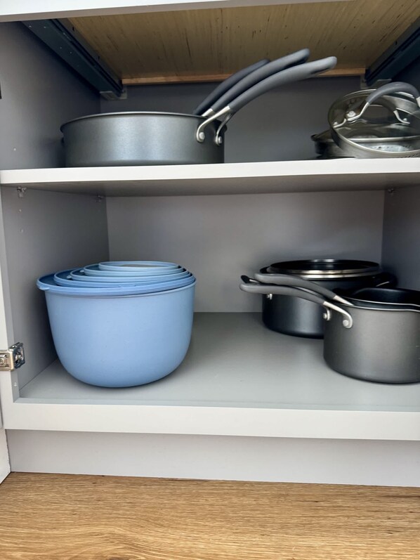 Un meuble de cuisine contenant des casseroles et des poêles.