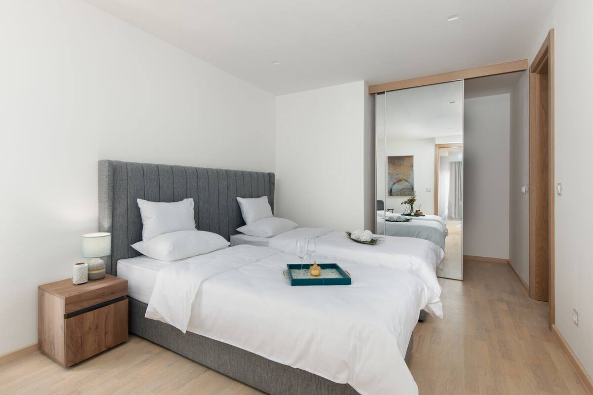 A modern hotel room with a large bed, bedside tables, and a mirror.
