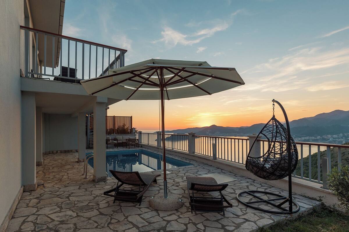 A rooftop pool area with lounge chairs, a hanging chair, and an umbrella.