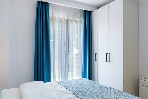A bedroom with a bed, a wardrobe, and a window with curtains. - Carsko Selo (Sveti Stefan)