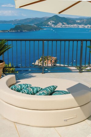 Un balcon avec vue sur la mer et une île lointaine.