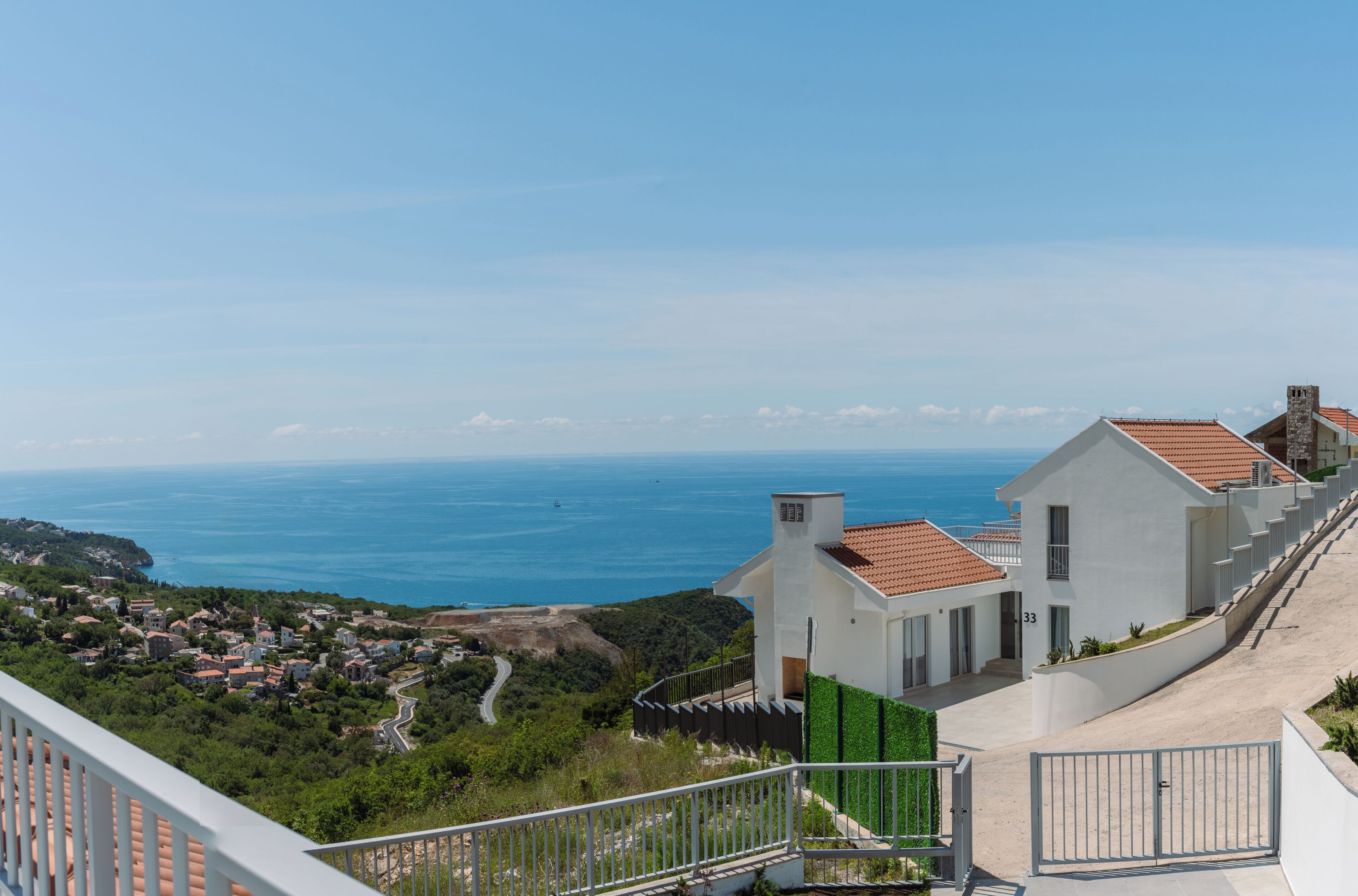 Un quartier résidentiel situé sur la côte, avec des maisons, un ciel bleu dégagé et une vue sur la mer.
